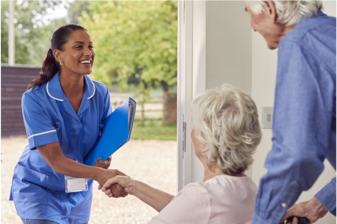 care worker greeting elderly couple